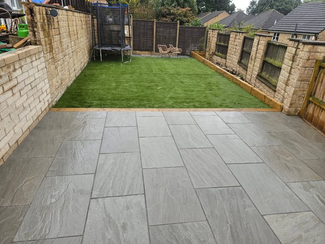 Grey paved patio leading to a lawn between garden walls