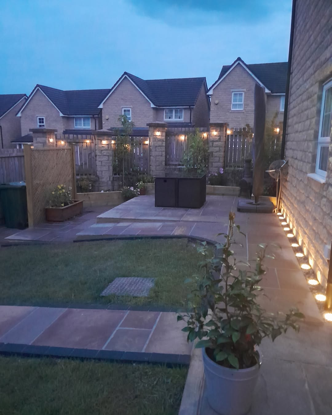 Completed garden with illuminated paths and lawn at dusk