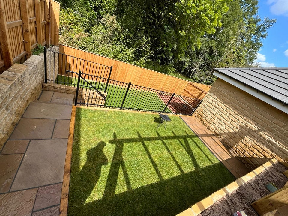 Compact lawn beside paving and a metal gate