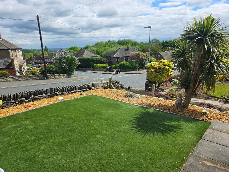 Artificial grass lawn beside decorative gravel and planting