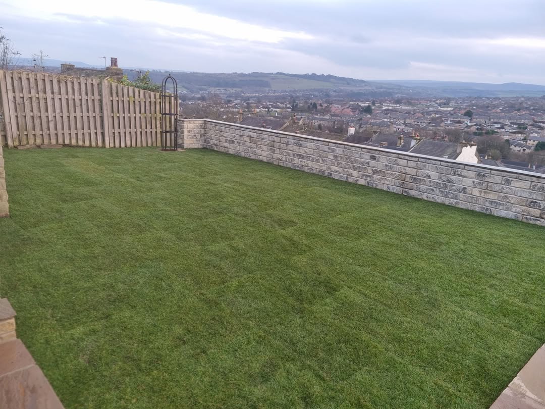 Turfed lawn beside a stone boundary wall